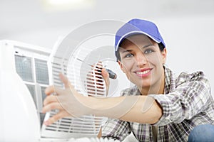 happy female worker repairing air conditioner