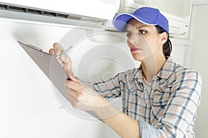 happy female worker repairing air conditioner