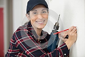 happy female worker with tool level and drill at work