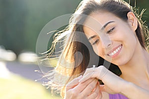 Happy fiancee looking at engagement ring in a park