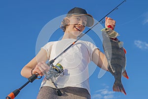 Happy fisher girl with perch fish trophy at the boat