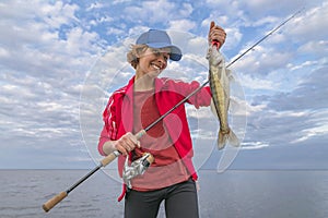 Happy fisher girl with walleye zander fish trophy at the boat