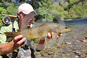 Happy fisherman with caught brown trout