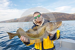 Happy fisherman with cod fish in hands