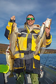 Happy fisherman with cod fish in hands