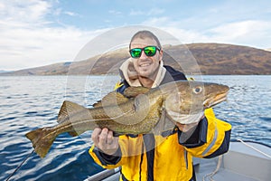 Happy fisherman with cod fish in hands