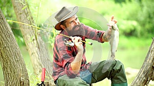 Happy fisherman fishing in river holding fishing rods. Fly angler man on the river. Trout. Holding brown trout. Man with