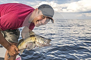Happy fisherman with walleye zander fish trophy at the boat
