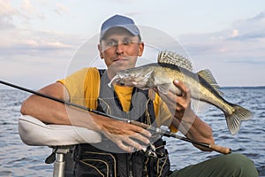 Happy fisherman with zander fish trophy at the boat photo