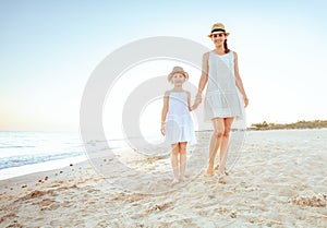 Happy fit mother and child tourists on seashore in evening