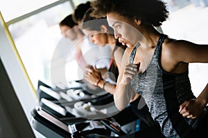 Happy fit people running on treadmill at fitness gym club