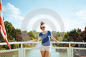 Happy fit solo tourist woman on river boat having river cruise