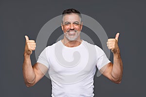 Happy fit sporty older man personal trainer showing thumbs up isolated on gray.