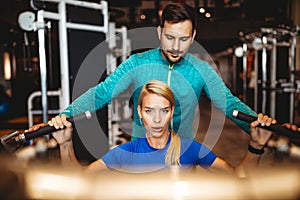 Happy fit woman exercising with her personal trainer in gym