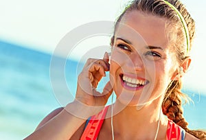 Happy fit woman on seacoast with headphones listening to music