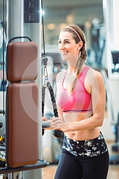 Happy fit woman wearing pink fitness bra while exercising at the gym