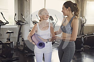 Happy fitness couple senior and young woman holding yoga mats