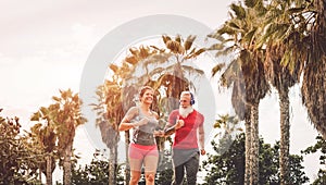 Happy fitness friends running at sunset outdoor - Couple of joggers training at evening time