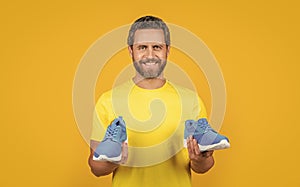 happy fitness man with sneakers on background. fitness man with sneakers in studio.