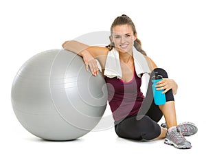 Happy fitness woman sitting near fitness ball