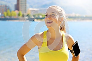 Happy fitness woman wearing activewear and sports smart phone armband blank for advertising for running or cardio workout on beach