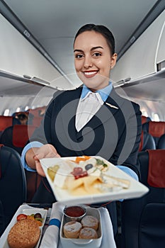 Happy flight hostess offering meal from catering trolley