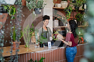 Happy florist selling plants and flower to client