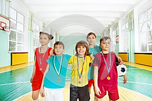 Happy football winners with medals in sports hall