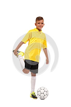 A happy footballer is warming up. A cheerful child in a football uniform isolated on a white background. Sports concept.