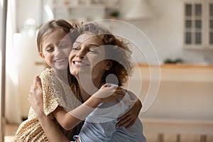 Happy foster mother and adopted daughter hug tight touch cheeks photo