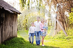 Happy four member family spending spring afternoon together outdoors in orchard