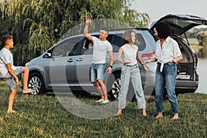 Happy Four Members Family Having Fun Time Outdoors, Mother Dancing with Teenage Daughter While Father Playing with Son