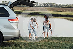 Happy Four Members Family Having Fun Time Outdoors by the River, Mother and Father with Two Teenage Children and Pet Dog