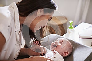 Happy four month old baby boy lying on changing table looking up at his mum, close up