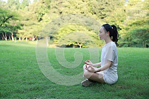 A happy free smile peace balance meditation beauty girl Asian Chinese lying laying on grass lawn thinking do yoga in forest park photo