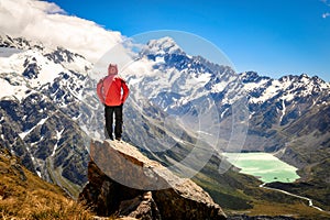 Happy free tourist man standing outstretched up looking at river and mountains landscape from Mueller Hut, MT. Cook - New Zealand