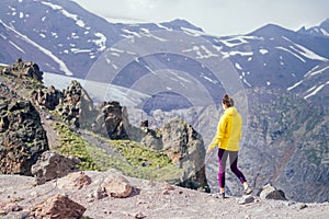 Happy free woman in yelllow jacket in summer Elbrus
