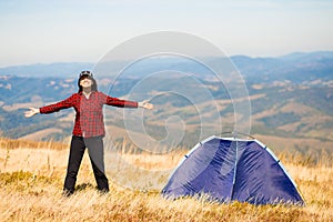 Happy freedom girl with hands up in mountains camping travel