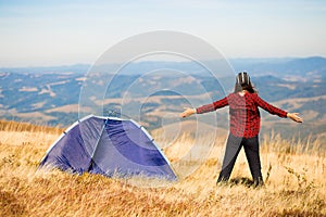 Happy freedom girl with hands up in mountains camping travel