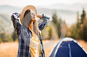 Happy freedom girl in straw hat with hands up in mountains travel