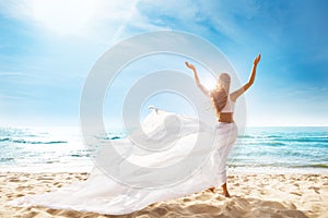 Happy Freedom Woman on Beach Enjoying Sun Arms Outstretched. Rear View of Girl Raised Hands fluttering White Dress on Wind. Summer