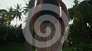 Happy freedom woman raised hands over palm trees in sunrise backlit enjoy her vacation