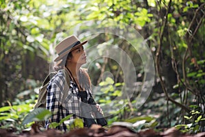 Happy freedom young woman watching wildlife with binoculars in nature park autumn, Tourist traveler backpack with copy space