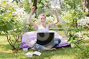 Happy freelancer working in the garden. Writing, surfing in the internet. Young woman relaxing and having fun in park area.