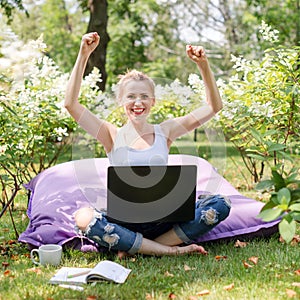 Happy freelancer working in the garden. Writing, surfing in the internet. Young woman relaxing and having fun in park area.