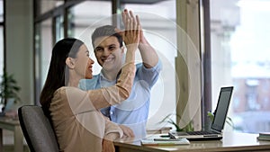 Happy freelancers giving high five and smiling, company achievement, success