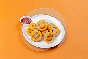 Happy French fried potato smiley faces with ketchup in a plate on a brown background