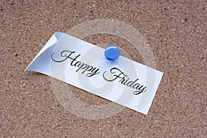 Happy Friday text on white stick note and pinned to a cork notice board.