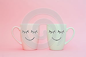 Happy friday word. Two cups of coffee stand together to be heart shape on pink background with smile face on cup.