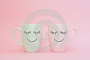 Happy friday word. Two cups of coffee stand together to be heart shape on pink background with smile face on cup.